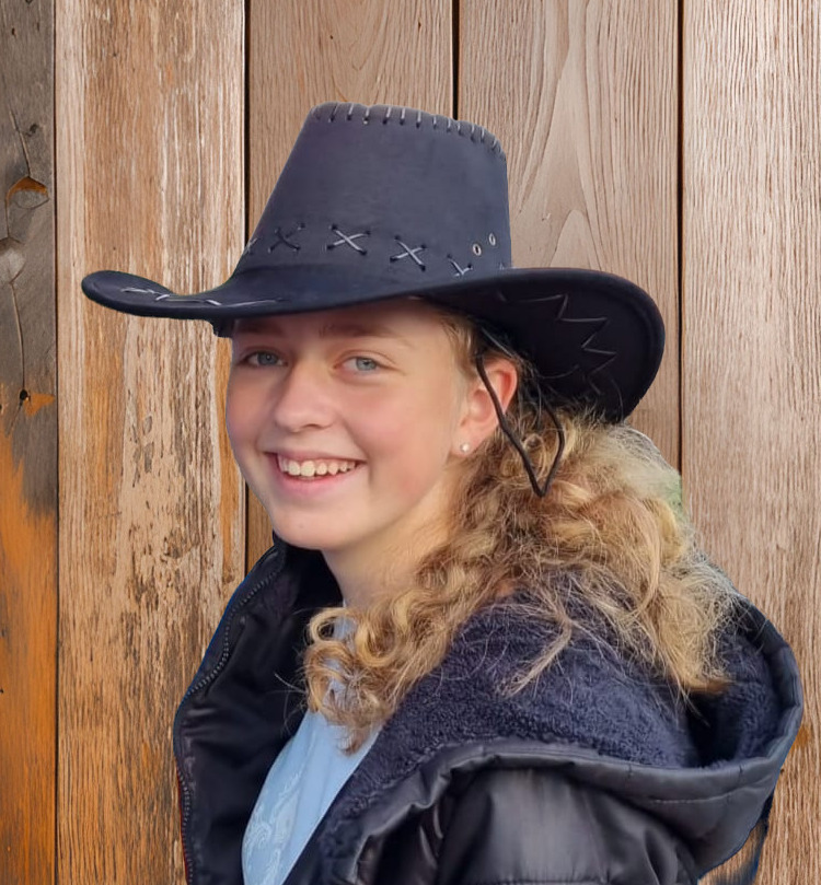 Sabrina Harder mit Cowboyhut vor Stallwand stehend in Nahaufnahme